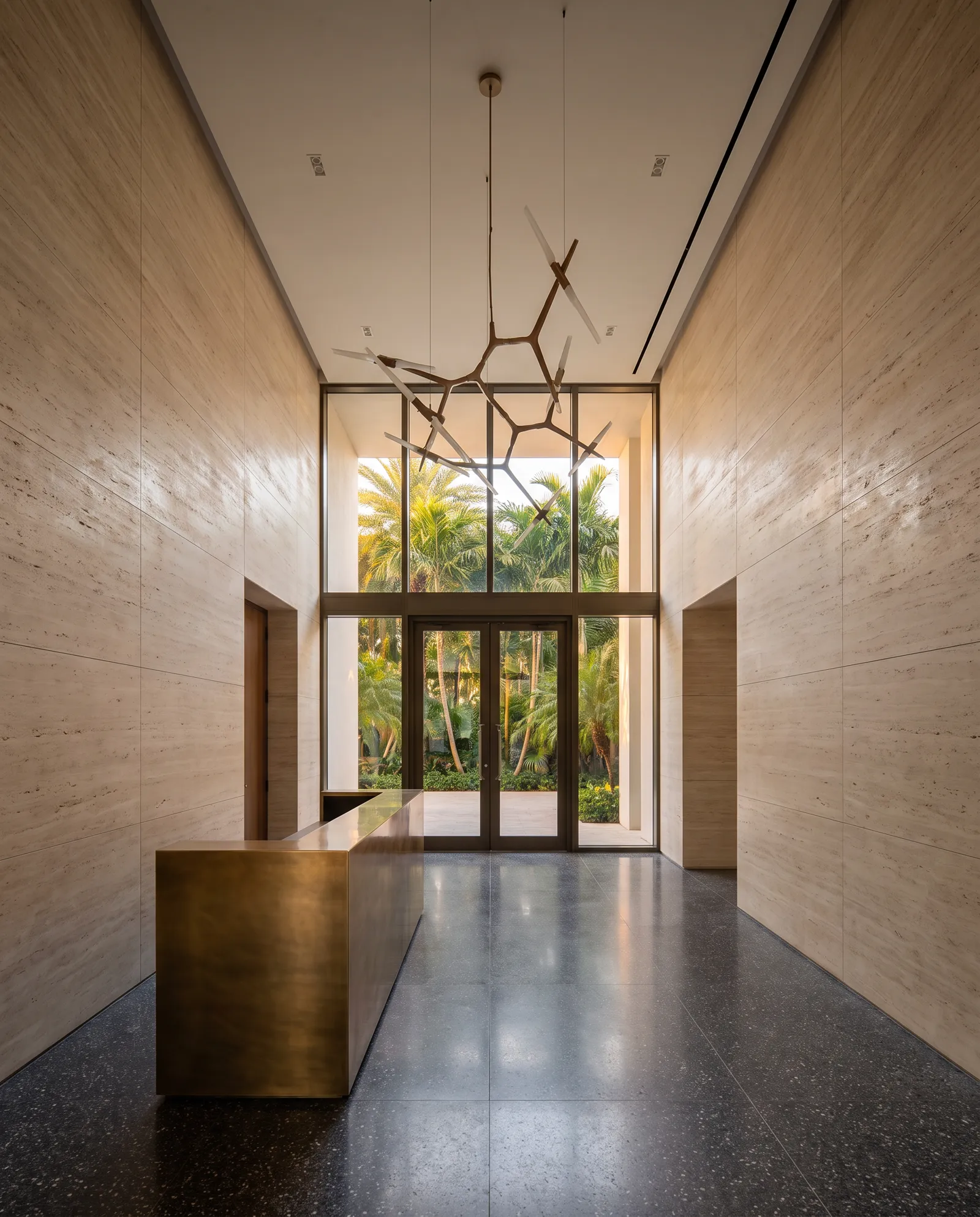 The lobby of a new luxury condominium with travertine walls and a bronze reception desk